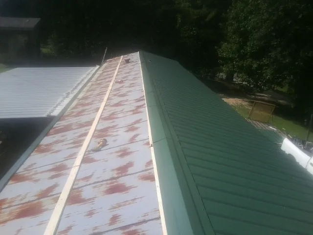 Old rusted panels beside newly installed green metal roofing — Wind Damage Roof Repair by Roofing Brothers in Jamesville