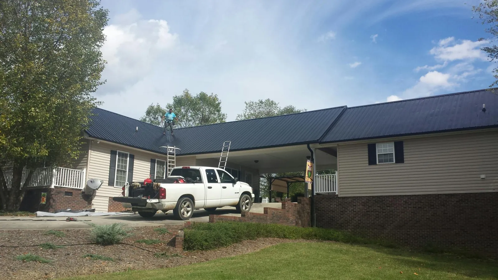 Black metal roof over a home and attached breezeway with ladders set in Jamesville